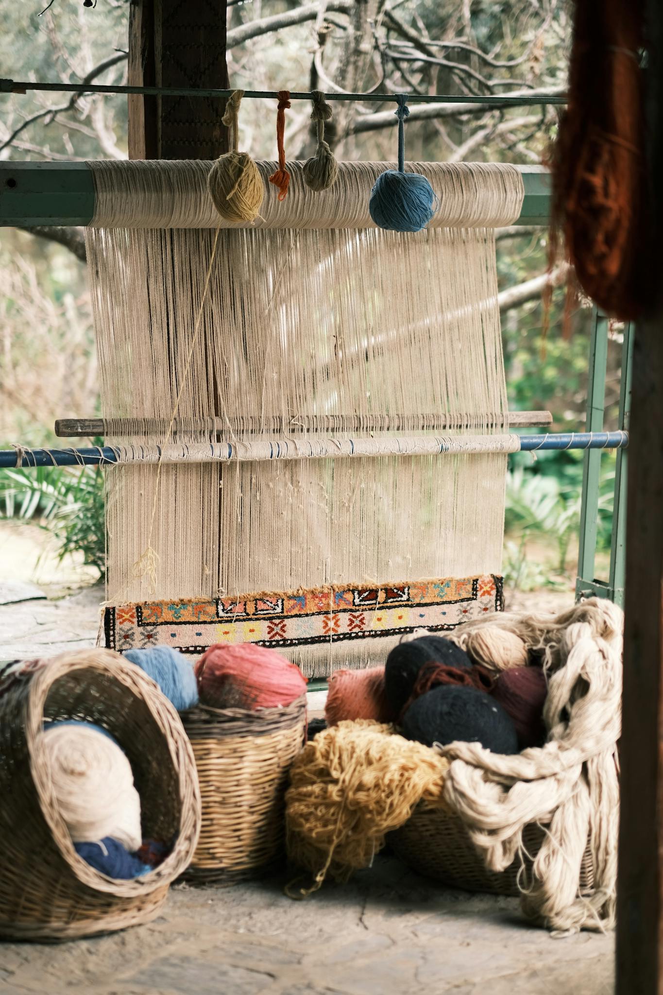 A traditional loom setup with colorful wool balls and wicker baskets, ideal for textile industry themes.