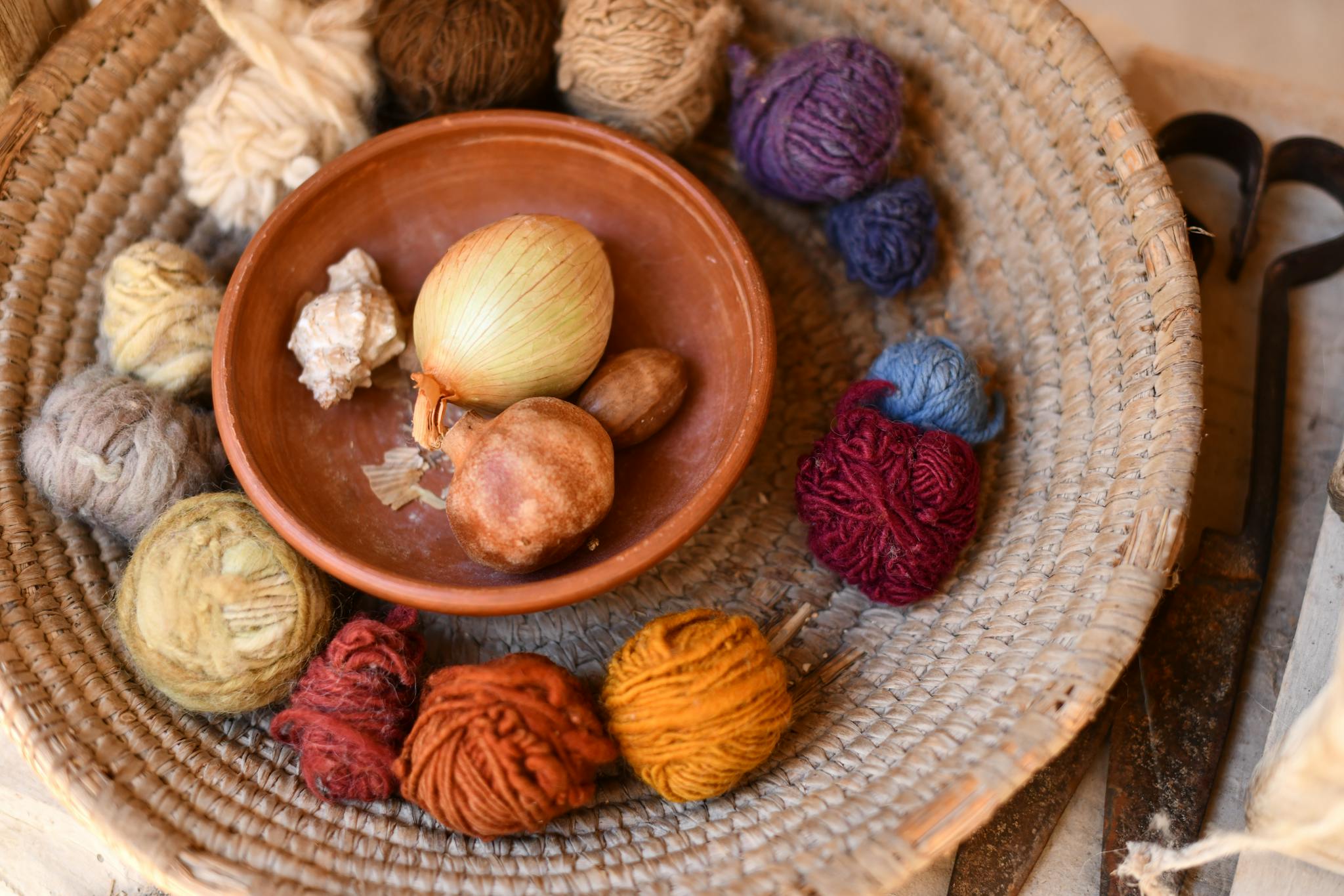 Close-up of colorful yarn balls with onion dye in a rustic basket, highlighting natural dyeing techniques.